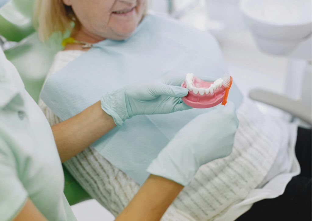 Dentist demonstrating proper denture care with a dental model to explain how long dentures typically last and when replacement may be needed.