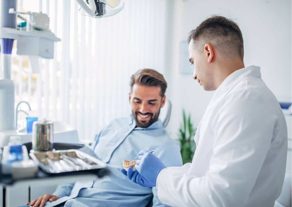 Dentist explaining the cost of a single tooth implant using a dental model during a personalized implant consultation.
